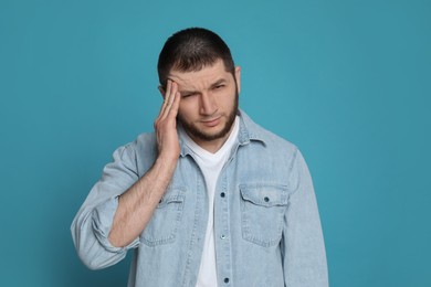 Man suffering from headache on light blue background