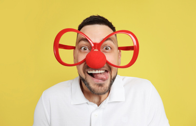 Funny man with clown nose and large glasses on yellow background. April fool's day