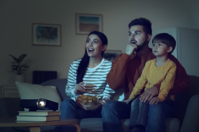 Emotional family watching movie at home, focus on video projector