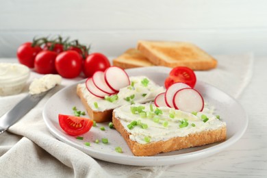 Toasted bread with cream cheese and vegetables on white wooden table