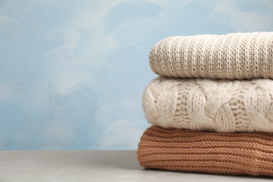 Photo of Stack of folded knitted sweaters on table. Space for text