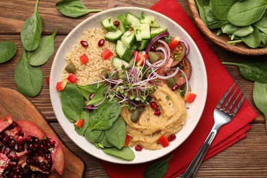 Photo of Delicious vegan bowl with cucumbers, spinach and bulgur on wooden table, flat lay