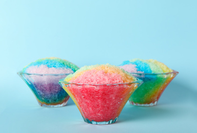 Rainbow shaving ice in glass dessert bowls on light blue background