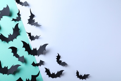 Many black paper bats on color background, flat lay with space for text. Halloween decor