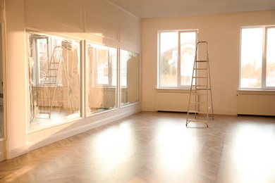 Spacious empty room with new parquet flooring and mirrors