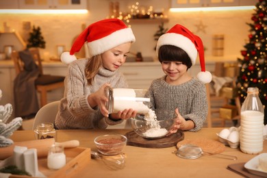 Cute little children making dough for Christmas cookies in kitchen