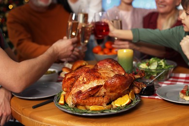 Family clinking glasses of drinks at festive dinner, focus on delicious baked turkey. Christmas celebration