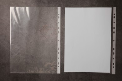 Photo of Punched pockets and paper sheet on grey table, top view. Space for text