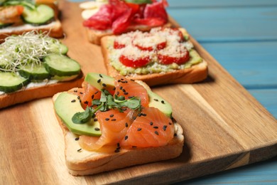 Photo of Tasty toasts with different toppings served on wooden board, closeup