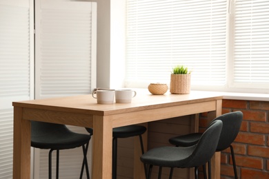 Stylish dining room interior with modern table set and window blinds