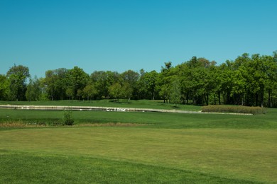 Photo of Picturesque view of golf course with fresh green grass and trees