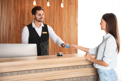 Client paying with credit card for service to receptionist at desk in lobby