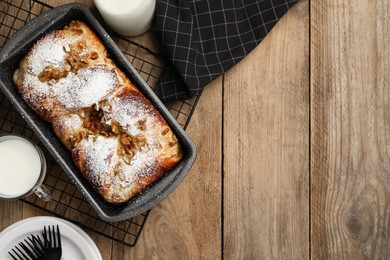Photo of Delicious yeast dough cake in baking pan and milk on wooden table, flat lay. Space for text