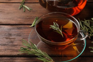 Aromatic herbal tea with rosemary on wooden table, space for text