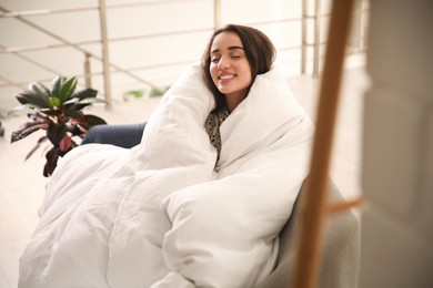 Photo of Beautiful young woman wrapped with soft blanket relaxing on sofa at home