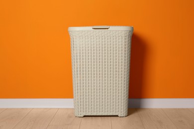 Photo of Empty laundry basket near orange wall indoors