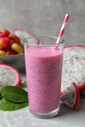 Glass of tasty pitahaya smoothie and fresh fruits on light grey table