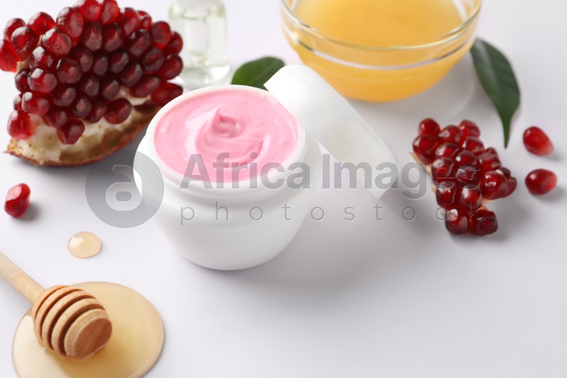 Photo of Jar of facial mask, pomegranate and fresh honey on white background. Natural organic cosmetics
