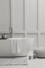 Modern ceramic bathtub near white wall indoors