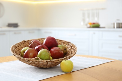 Fresh ripe apples and pears on wooden table in kitchen. Space for text