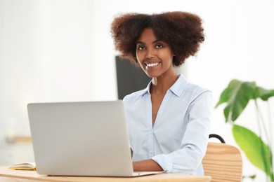 Photo of Smiling African American woman working on laptop indoors