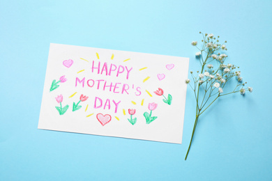 Handmade greeting card for Mother's day and flower on light blue background, flat lay