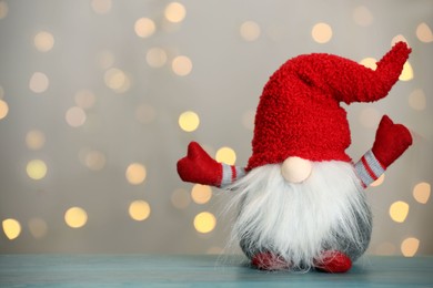 Cute Christmas gnome on turquoise wooden table against blurred festive lights. Space for text