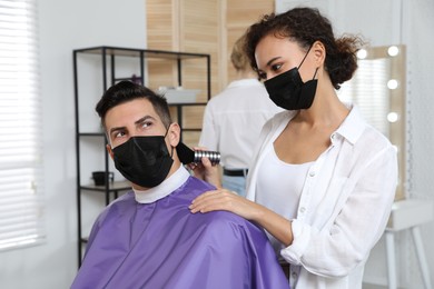 Photo of Professional stylist working with client in salon. Hairdressing services during Coronavirus quarantine