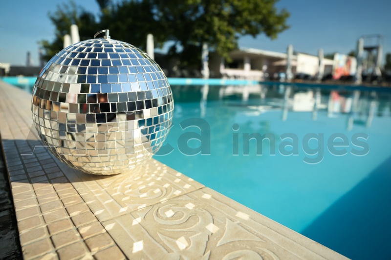 Shiny disco ball on edge of swimming pool. Party decor