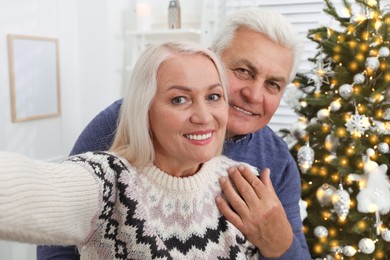 Happy mature couple taking selfie at home. Christmas celebration