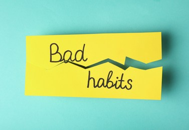 Torn paper with words Bad Habits on turquoise background, top view