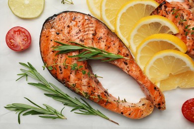Photo of Tasty grilled salmon steak and ingredients on white table, flat lay