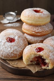 Delicious donuts with jelly and powdered sugar on wooden board, closeup
