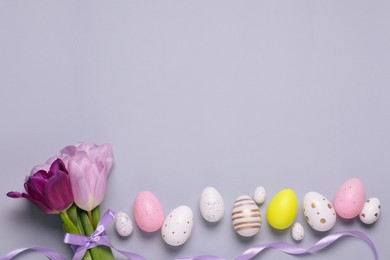 Photo of Flat lay composition with festively decorated Easter eggs on grey background. Space for text