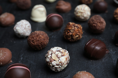 Different delicious chocolate candies on black table, closeup