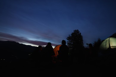 Group of friends near camping tents outdoors in evening