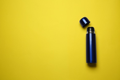 Blue thermos on yellow background, top view. Space for text