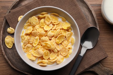Tasty cornflakes with milk in bowl served on wooden table, flat lay