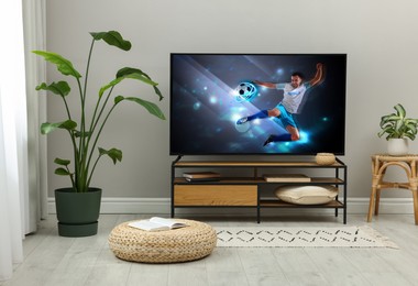 Modern TV set on wooden stand in room. Scene of football broadcasting