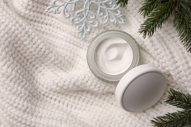 Photo of Winter skin care. Hand cream and fir branches on white knitted cloth, flat lay. Space for text
