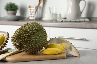 Fresh ripe durian fruits on grey table in kitchen, space for text