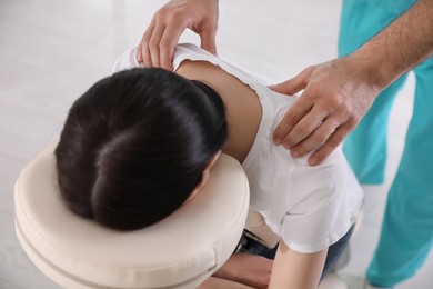 Woman receiving massage in modern chair indoors, above view