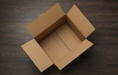 Empty open cardboard box on wooden table, top view
