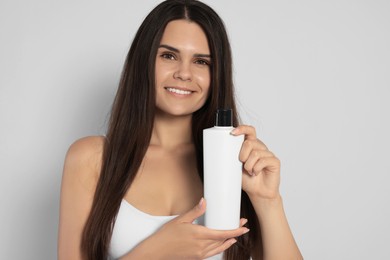 Photo of Beautiful young woman holding bottle of shampoo on white background