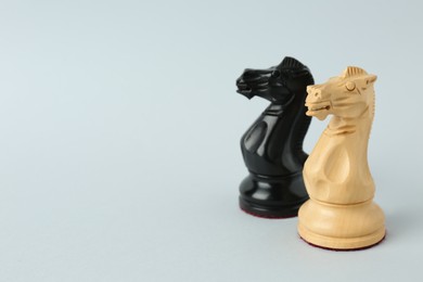 Black and white knights on light background, space for text. Chess pieces