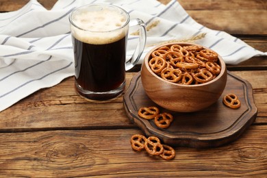 Delicious pretzel crackers and glass of beer on wooden table