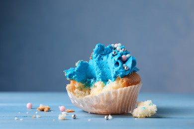 Failed cupcake on blue wooden table, closeup. Troubles happen