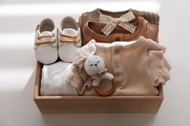 Wooden crate with children's clothes, shoes and toy on white table
