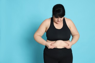 Obese woman on light blue background. Weight loss surgery
