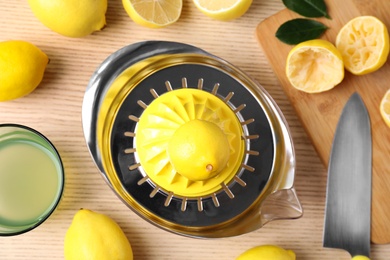 Flat lay composition with fresh lemons and juicer on wooden table